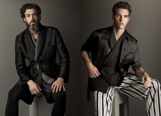 Bearded man in dark jacket; clean-shaven in casual black-striped outfit.