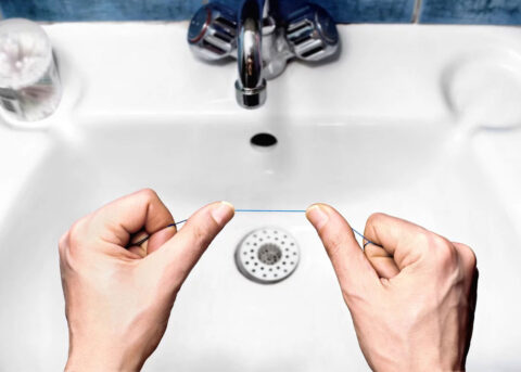 Holding dental floss over a shiny sink.