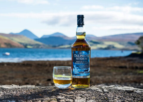 Talisker whisky bottle beside tranquil scenic view.