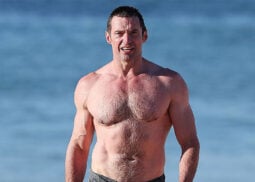 Muscular man with short dark hair on beach.
