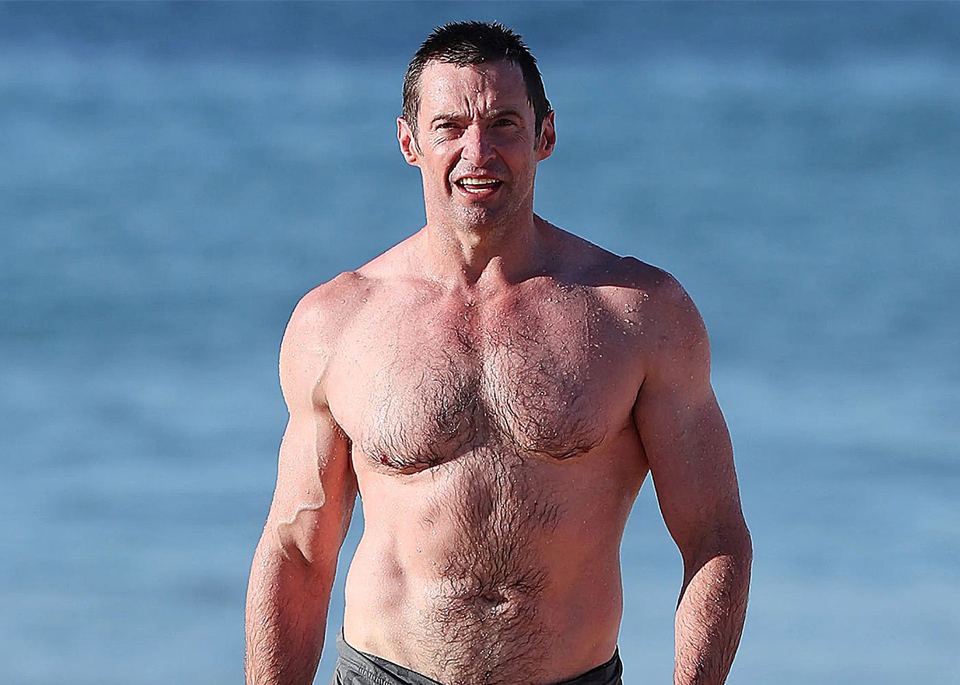 Muscular man with short dark hair on beach.