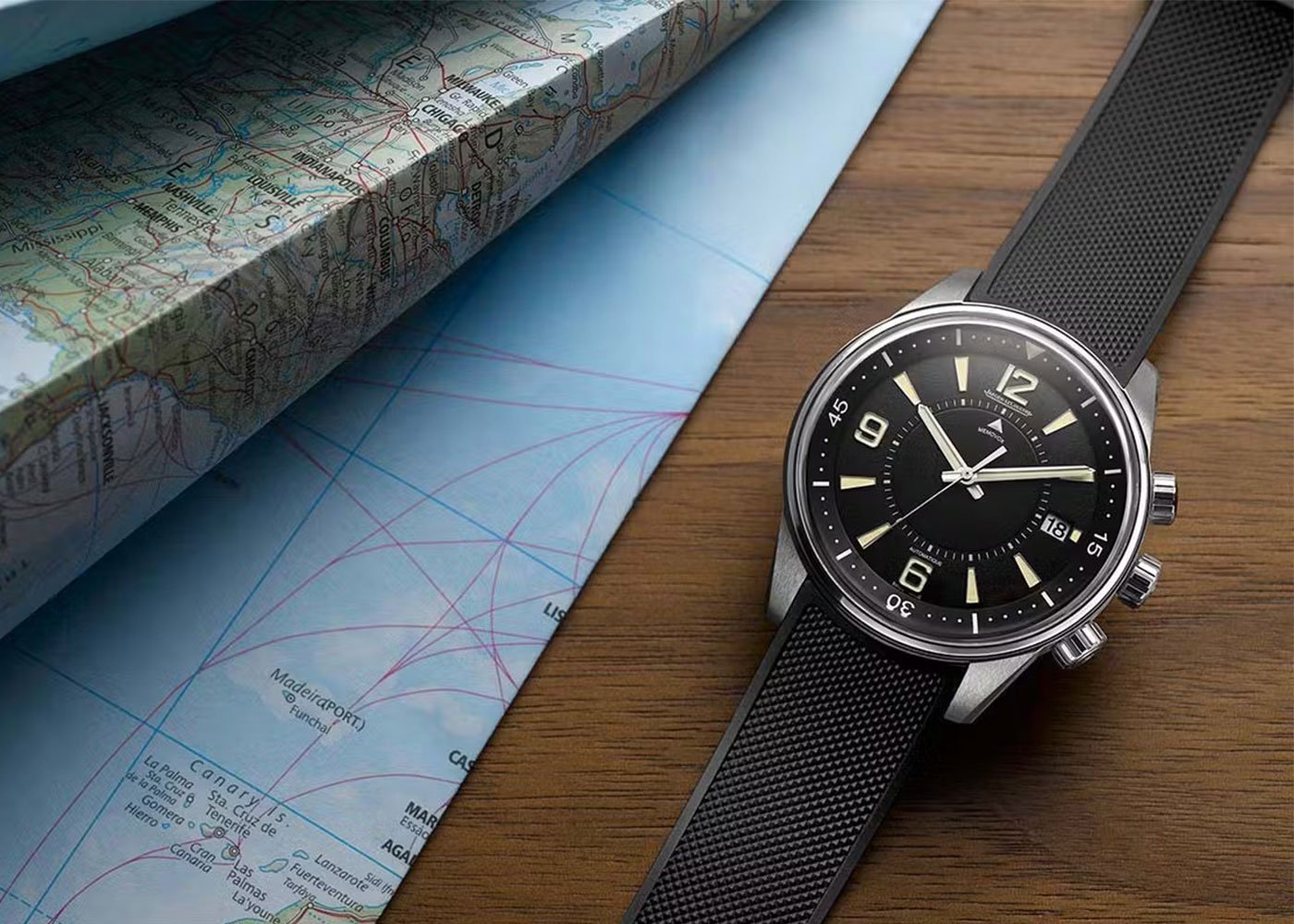 Jaeger-LeCoultre watch on wood beside map.