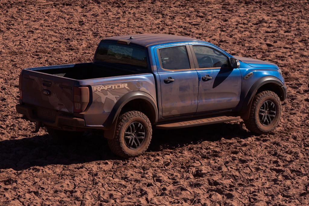 Blue Ford Raptor truck on rugged terrain.