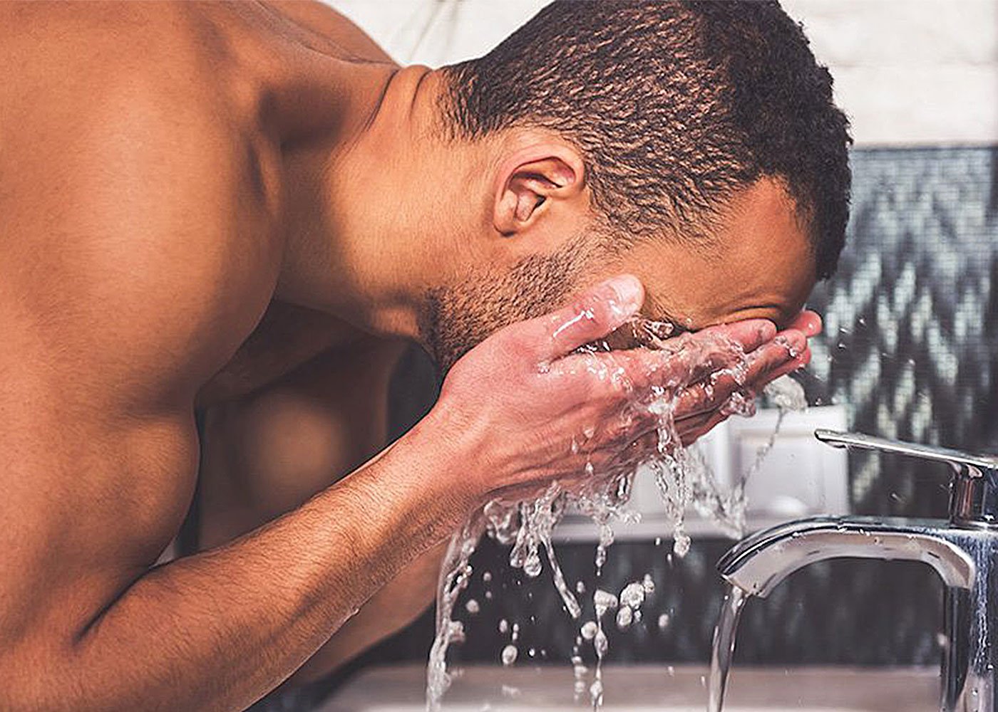 Person washing face, avoiding bad skincare habits.