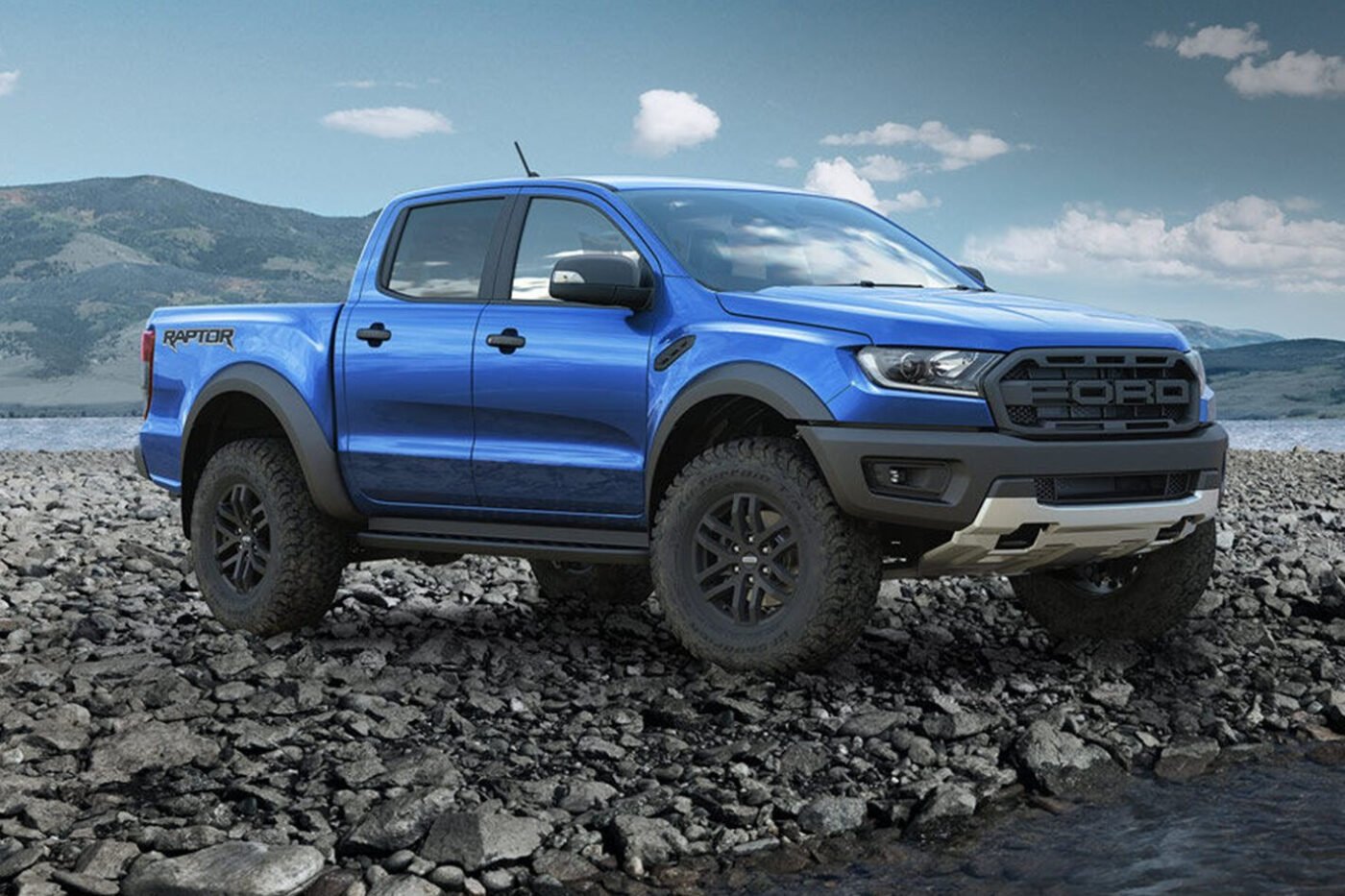 Blue Ford Raptor parked on rocky terrain.