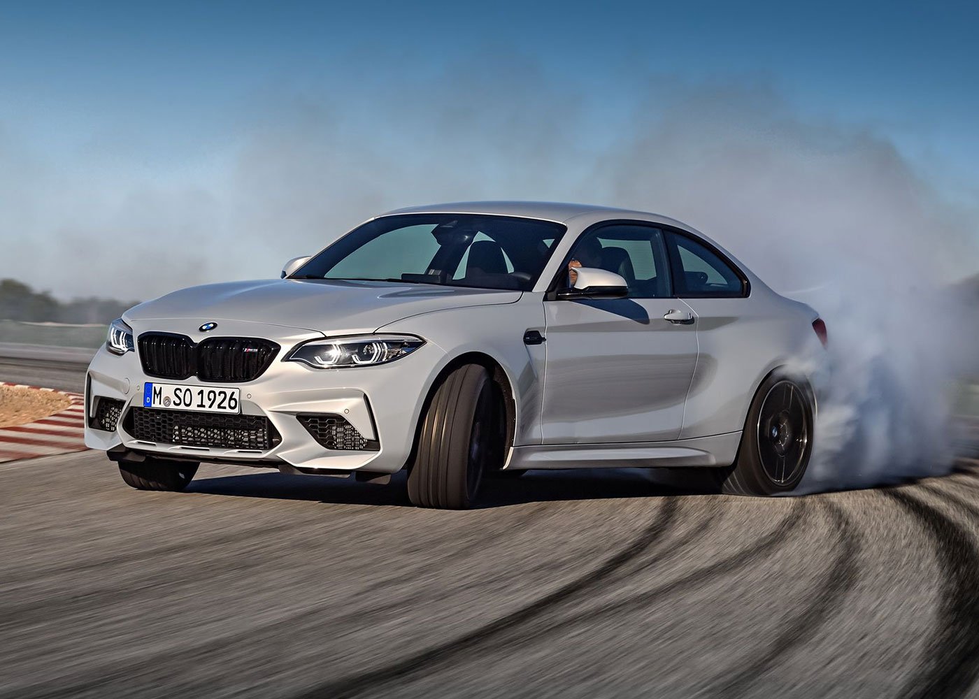 BMW M2 Competition drifts, leaving tire smoke.