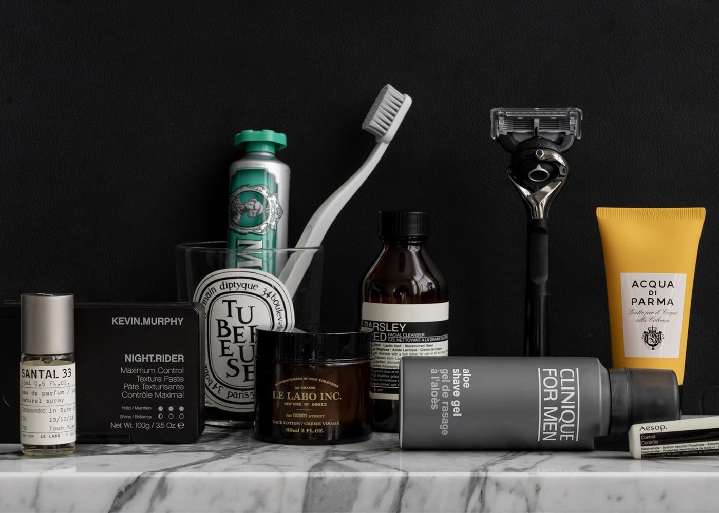 Travel grooming essentials on marble and black backdrop.