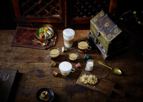 Steaming coffee with pastries and colorful pods.