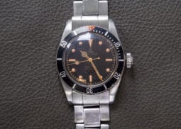 Tudor Submariner watch with black dial, stainless bracelet.