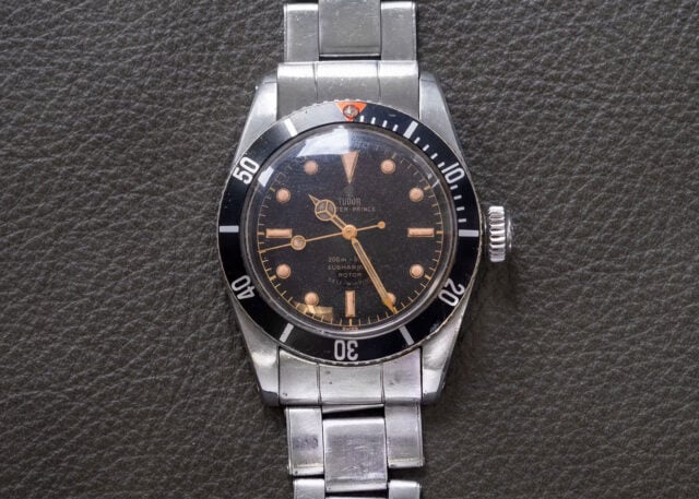 Tudor Submariner watch with black dial, stainless bracelet.