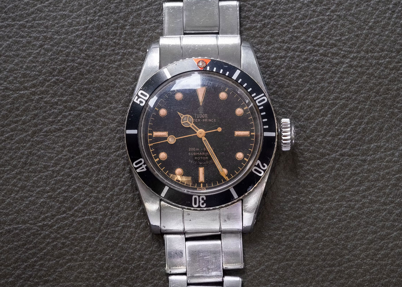 Tudor Submariner watch with black dial, stainless bracelet.