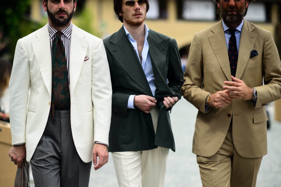 Three suited men walk together.