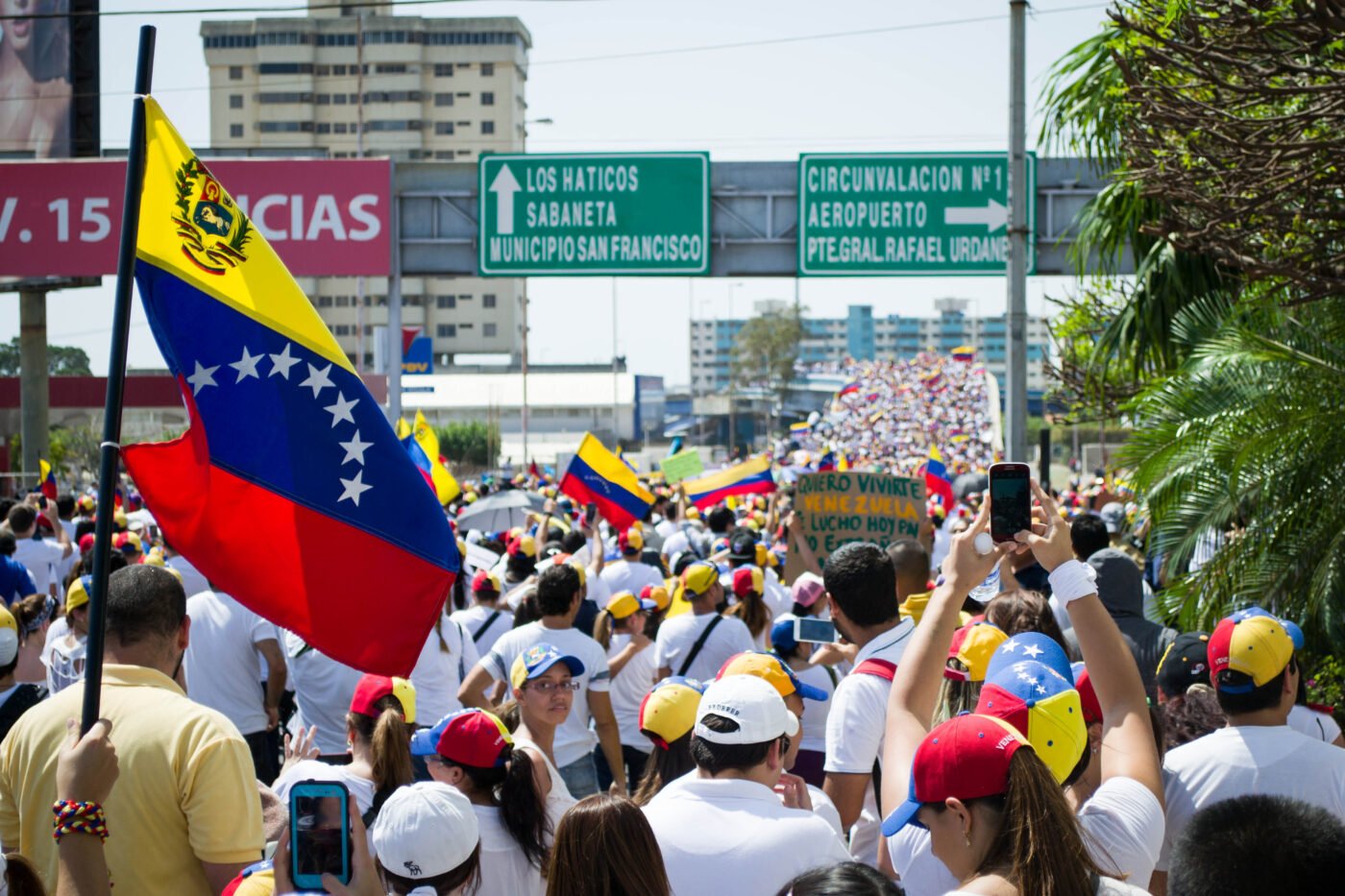Crowds in white shirts hold Venezuelan flags.