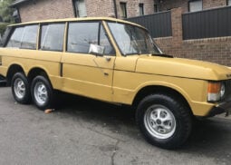 A worn vintage Range Rover SUV on street.