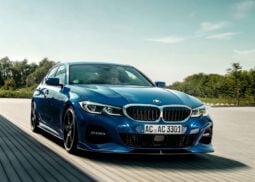 A blue BMW 3-Series sedan on paved road.
