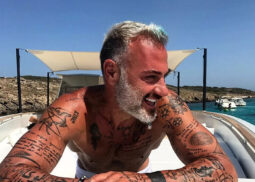 Shirtless man with tattoos on a boat.