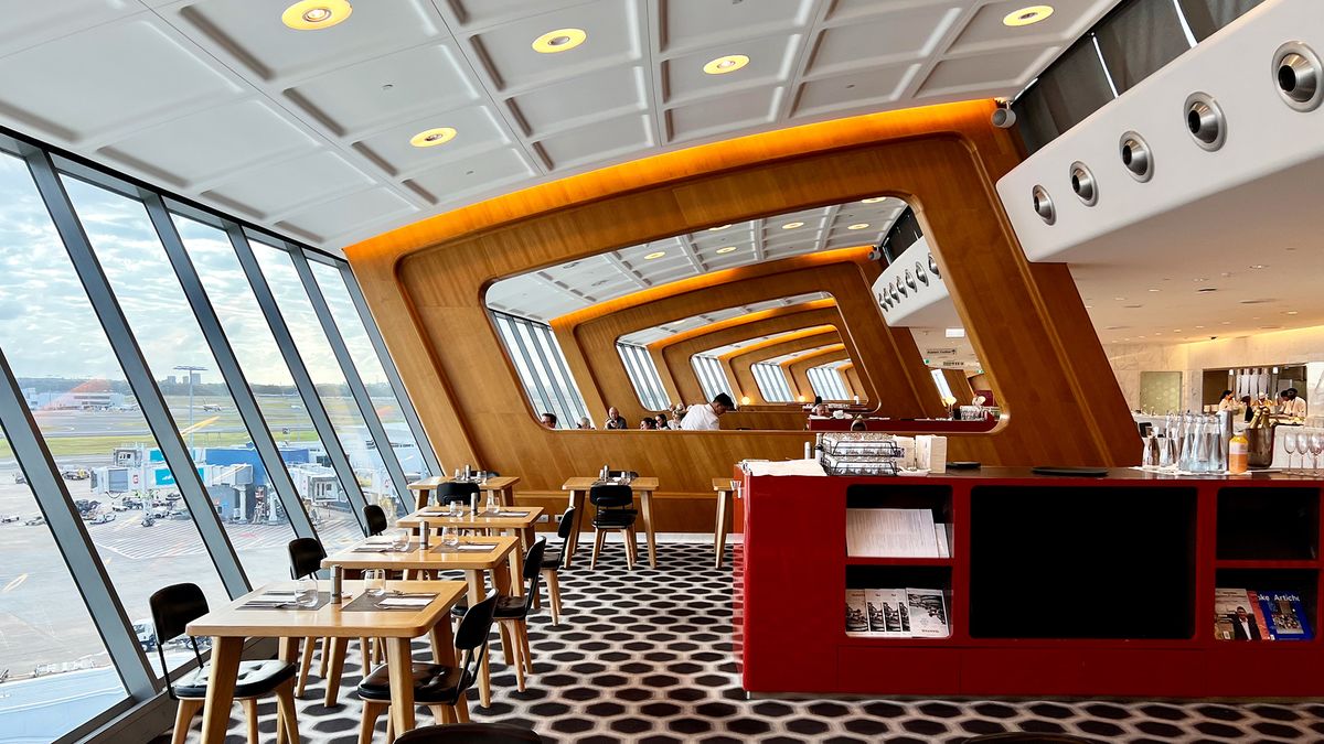 Airport lounge: runway views, wooden frames, red counter.