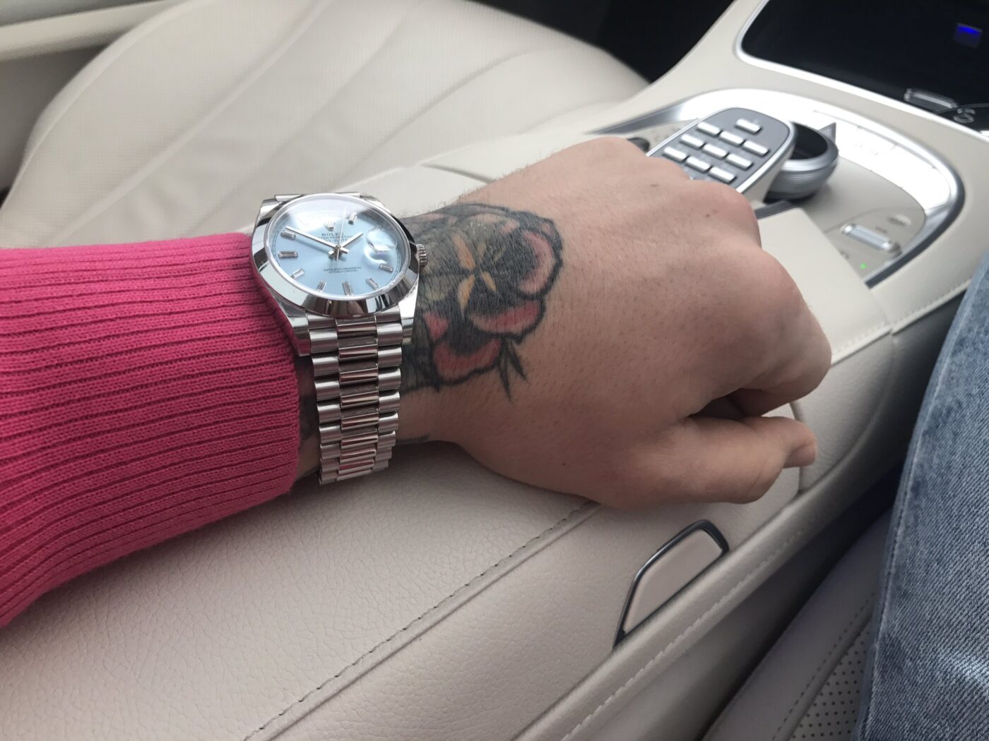 Wearing Rolex watch, pink shirt, and jeans.