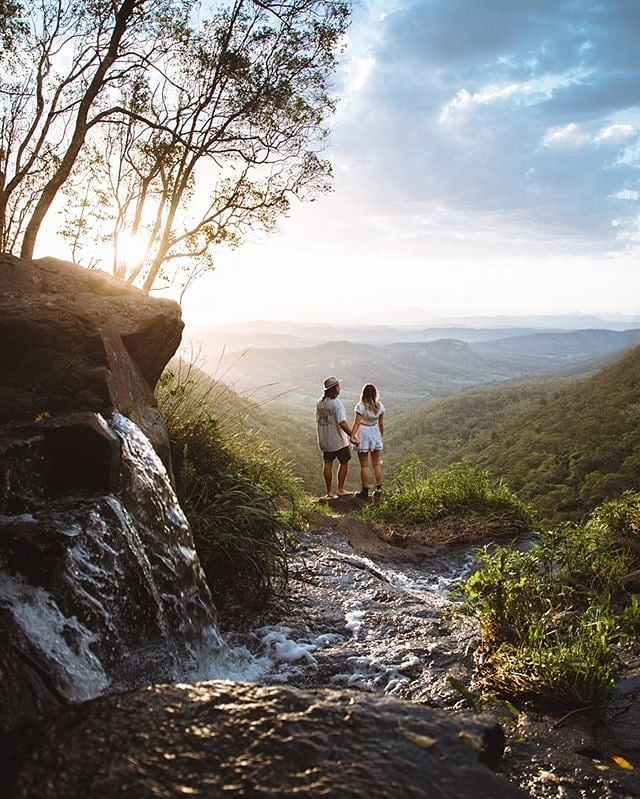 Couple holds hands, cliffside in Australia, 2022.