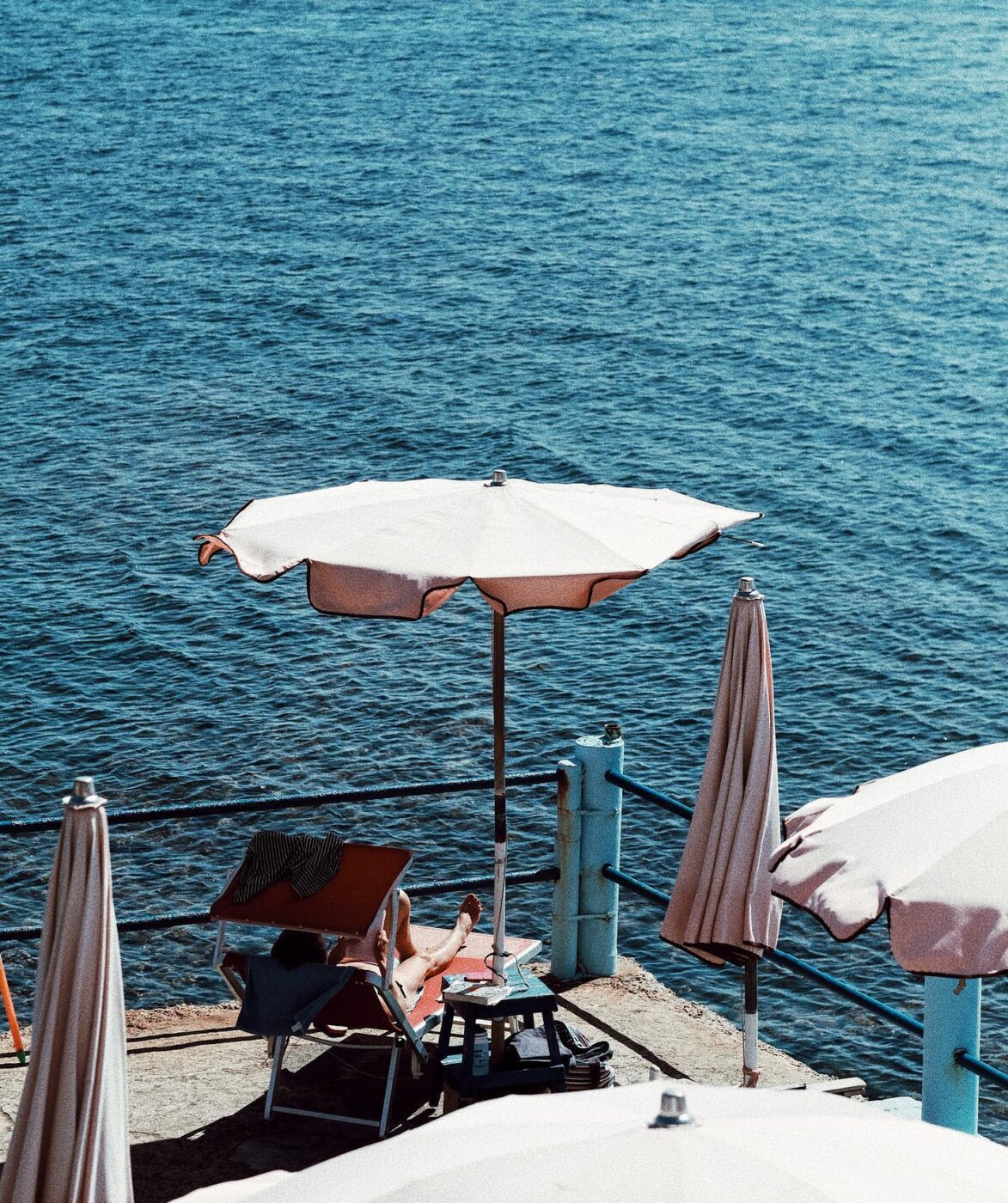 Person relaxes by Australian seaside under umbrella.