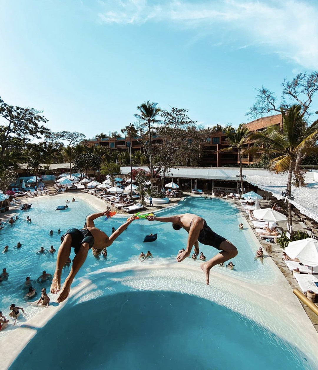 Two people jump into Bali-like pool.