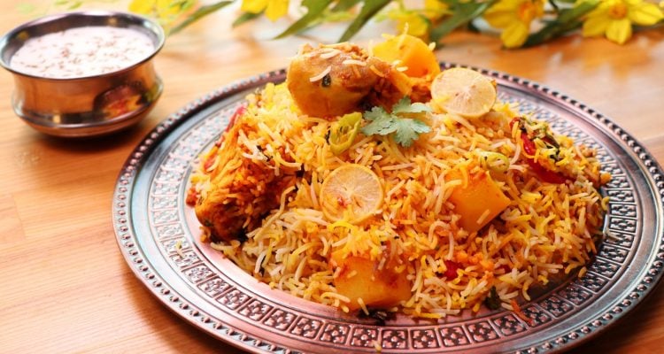 Biryani with lemon, cilantro on silver plate.