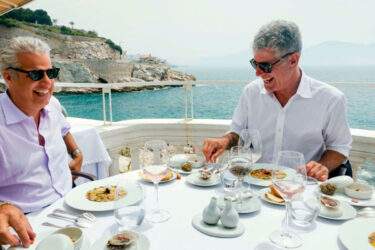 Two chefs dining seaside, enjoying ocean views.