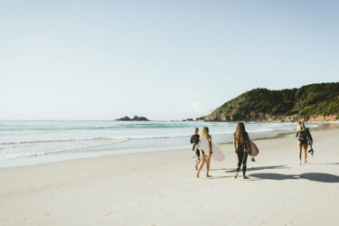 Surfers at Byron Bay's tranquil Main Beach.