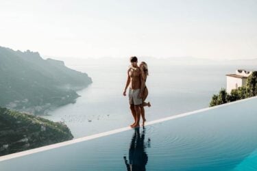 Couple embraces by infinity pool with scenic view.