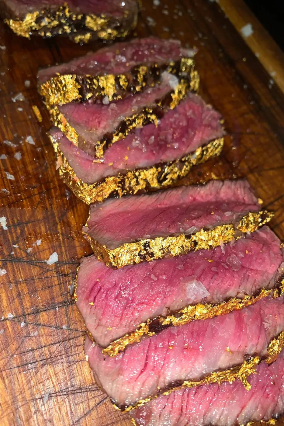 Medium-rare steak, gold garnish, Salt Bae-style.