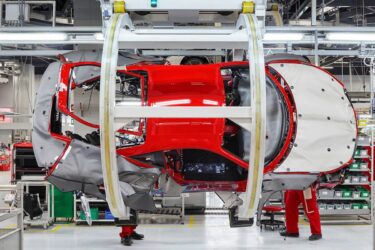 Workers in red assemble car in Australia.