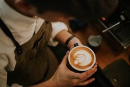 Barista with latte art prepares coffee orders.