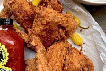 Fried chicken with peppers and sauce bottle.