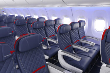 Plane cabin features quilted seats, overhead compartments.