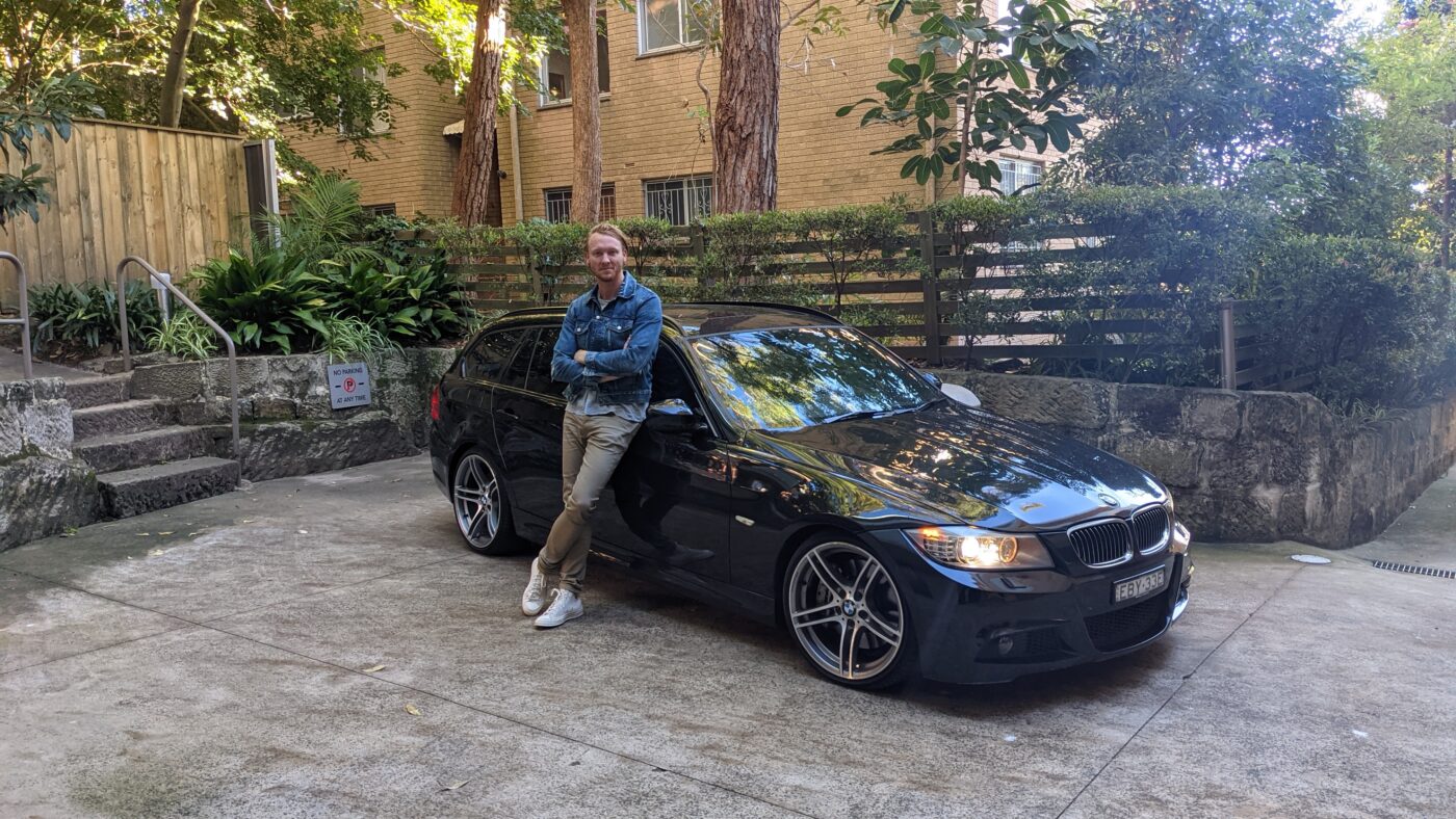 Person leans emotionally against BMW before selling.