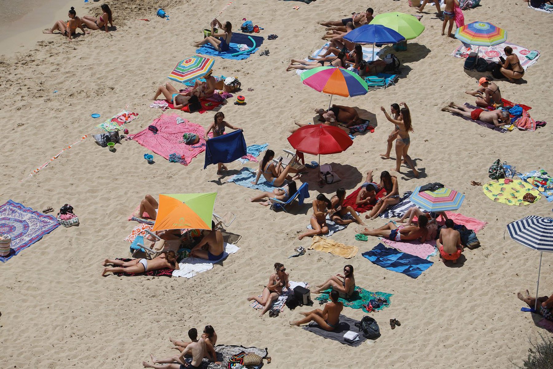 Beachgoers in swimwear sunbathing in Spain.