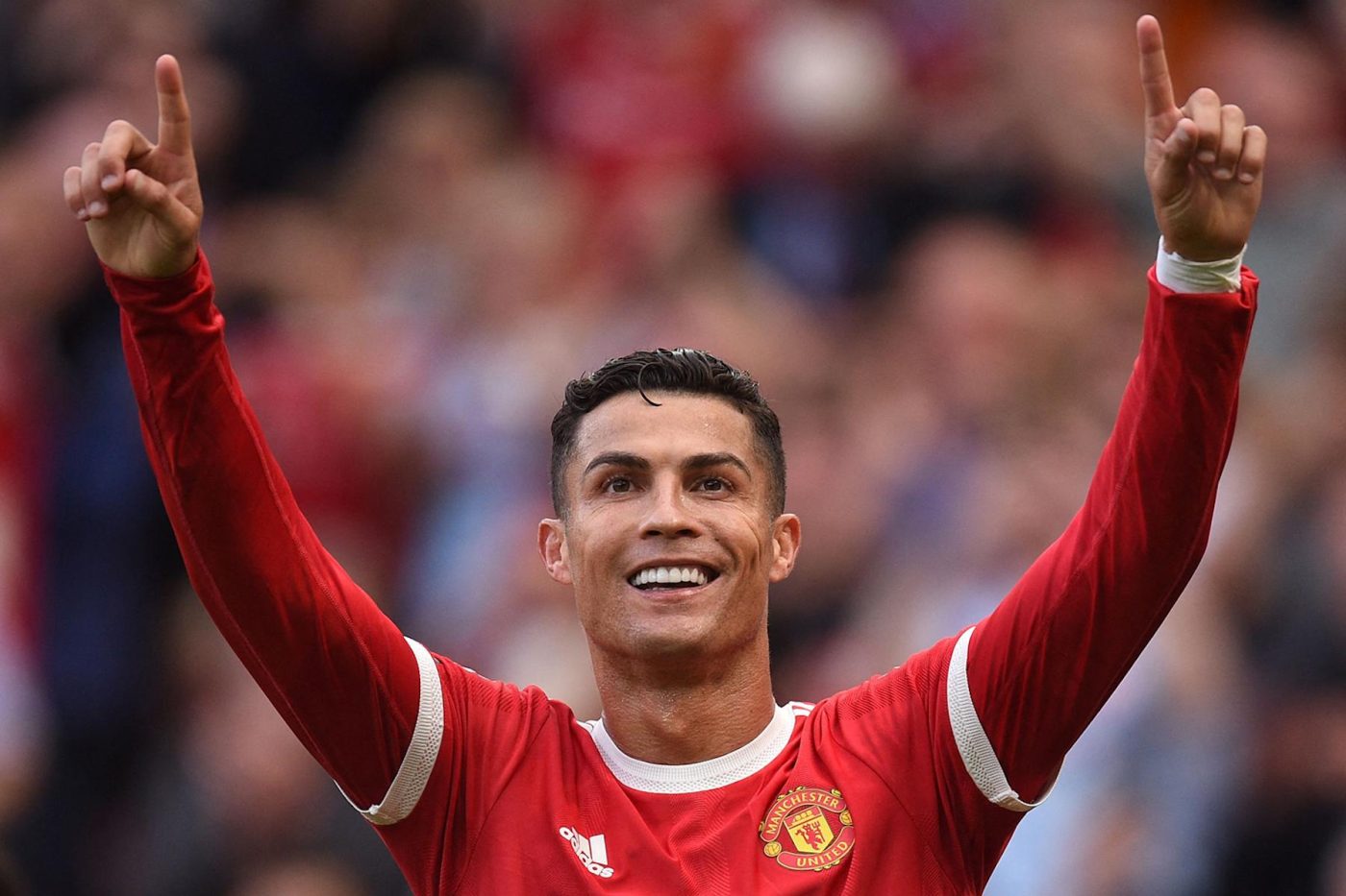 Cristiano Ronaldo celebrates; blurred crowd behind.