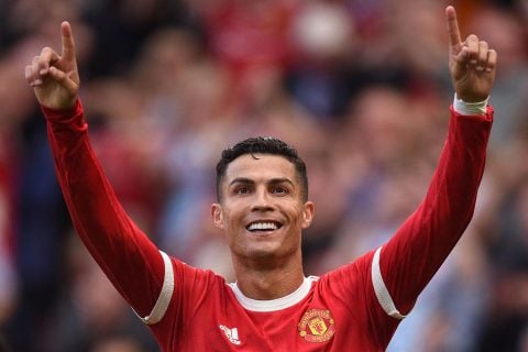 Cristiano Ronaldo celebrates; blurred crowd behind.