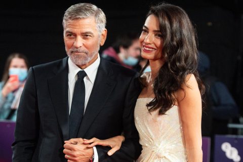 Couple poses on red carpet; he wears OMEGA.