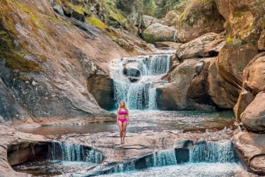 Person in swimsuit enjoys Wollongong waterfall serenity.