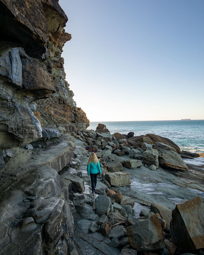 Someone in turquoise walks along Australia's coast.