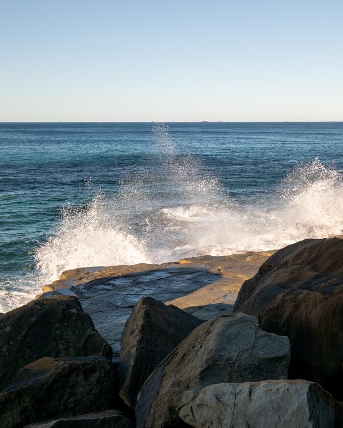 Waves crash on rocks, echoing Australia's coastlines.
