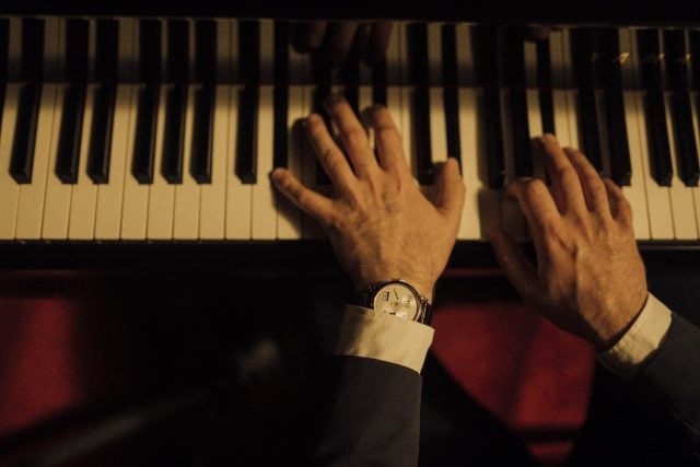 Pianist wears Swiss watch; elegance in harmony.