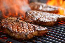 Grilled steaks with visible marks and flames.