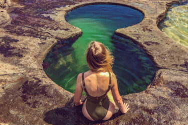 A woman sits near Figure 8 Pools.