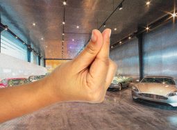 Hand gestures in luxury car showroom setting.