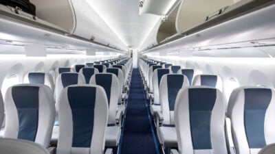 Empty airplane cabin with blue seats, serene lighting.