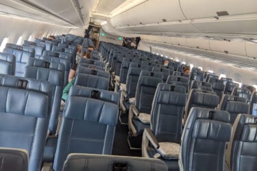 Nearly empty airplane cabin with navy seats.