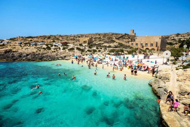 Busy Mediterranean beach with turquoise waters in Gozo.