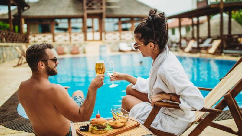 Travelers relax by pool at charming Airbnb.